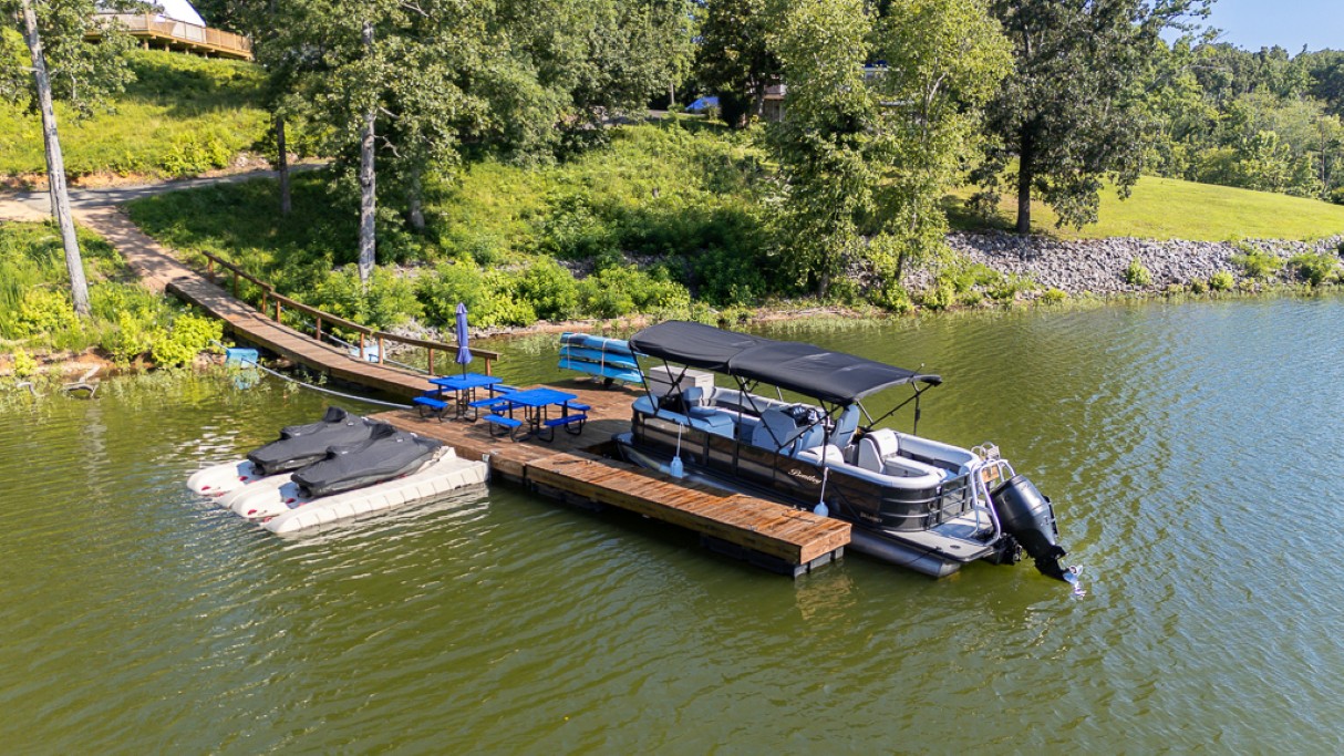 Private lakefront dock with pontoon boat rental, jet ski slips, and lakeside seating — steps from your dome.