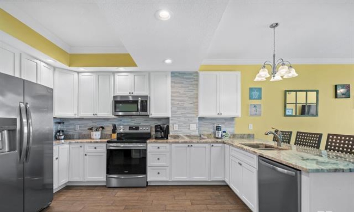 ENLARGED kitchen with stainless steel appliances (electric range, above range microwave, dishwasher, fridge with ice maker, solid wood cabinets, granite countertops and tiled backsplash