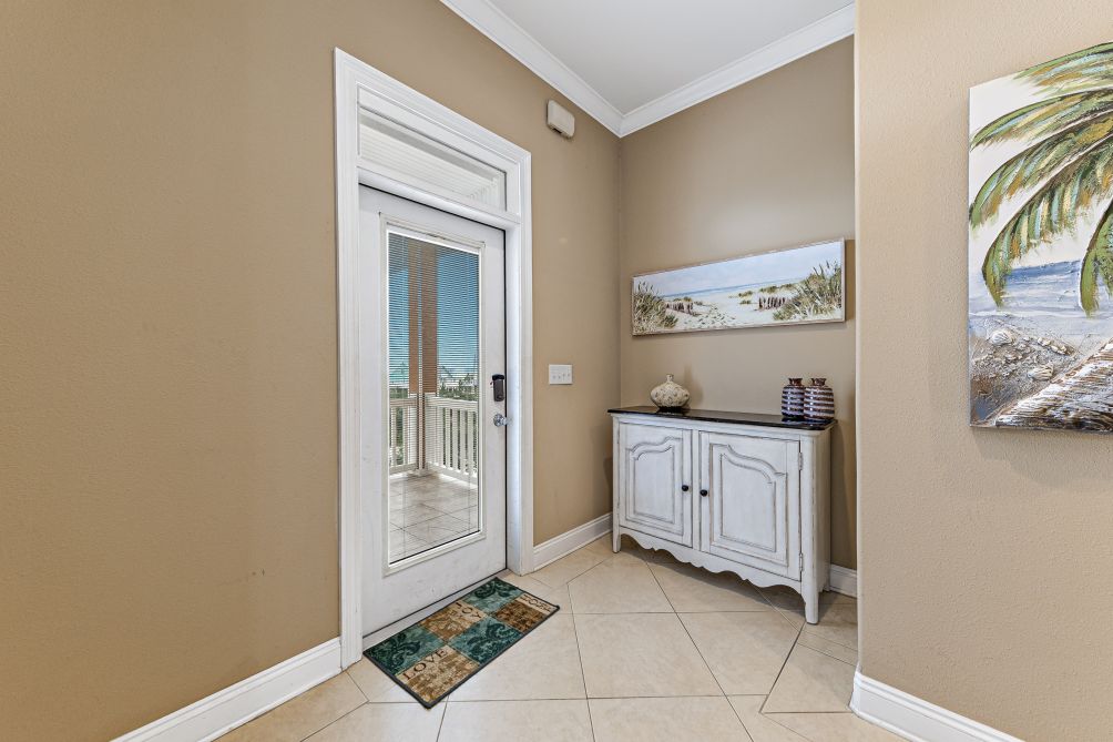 Tiled entry foyer with coastal decor and a glass door opening to the covered deck