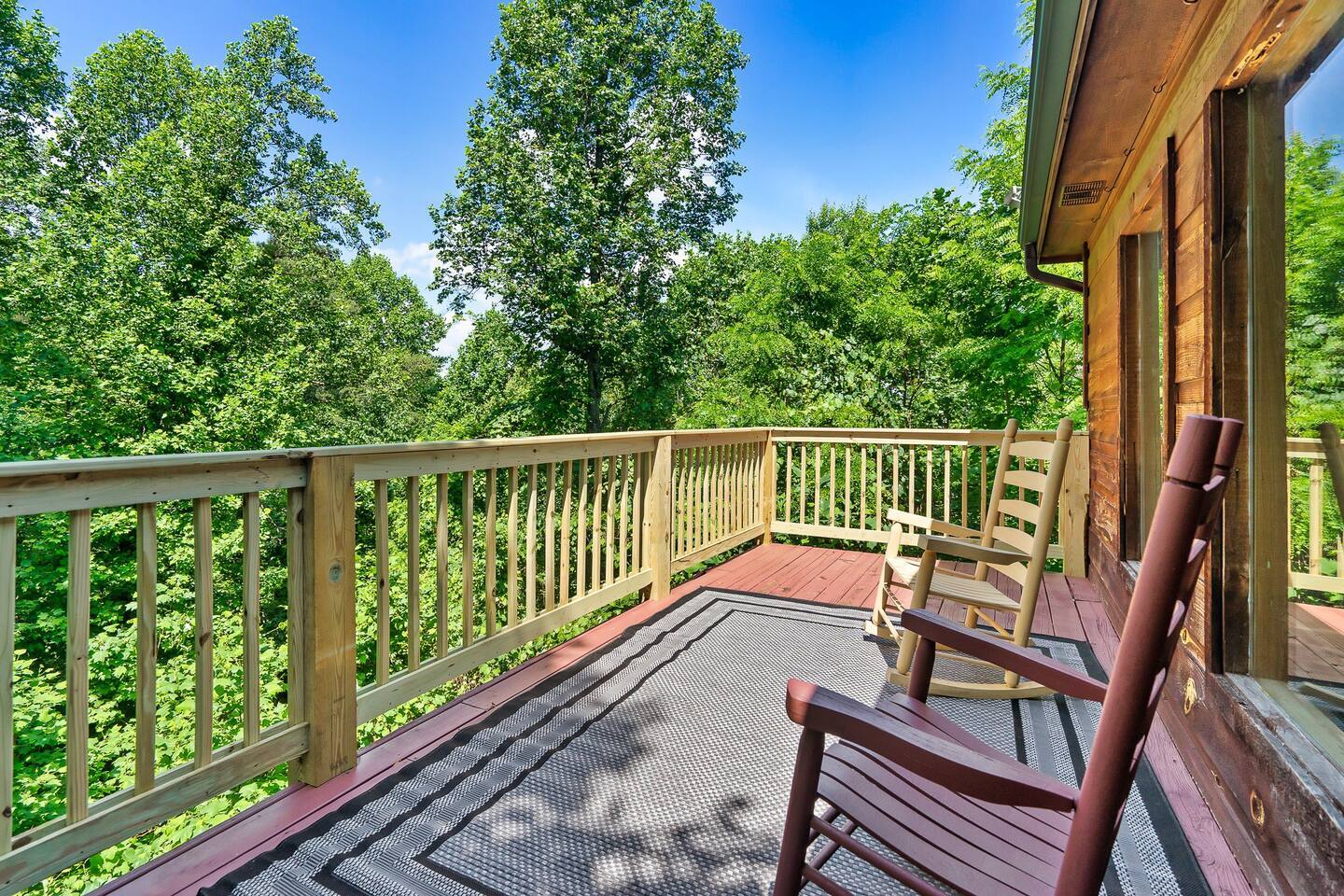 A serene cabin deck with rustic rocking chairs invites you to unwind while taking in the stunning natural surroundings and enjoying the sounds of nature.