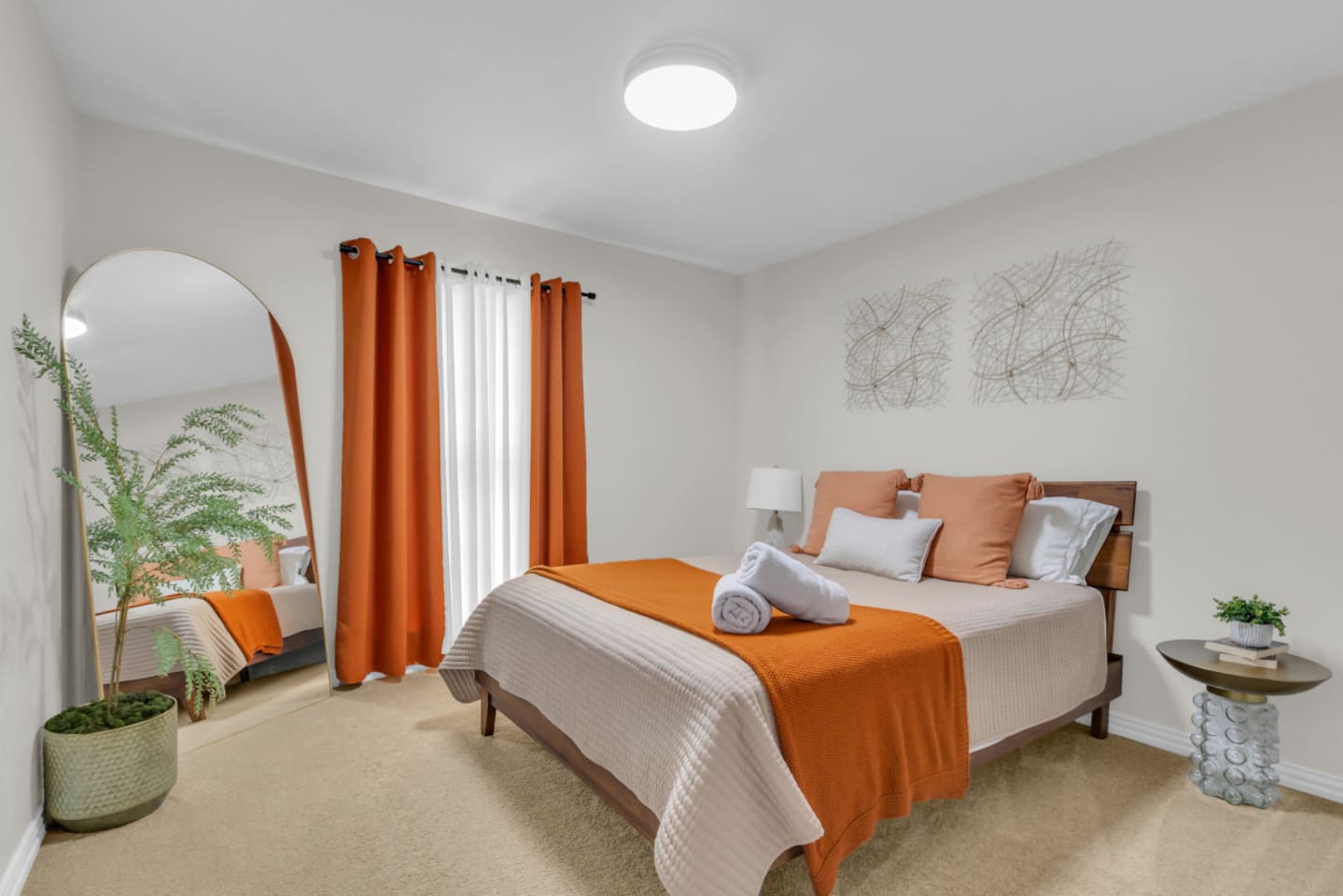 Bold orange accents, black out curtains and a full length mirror make this queen sized guest bedroom feel like home!