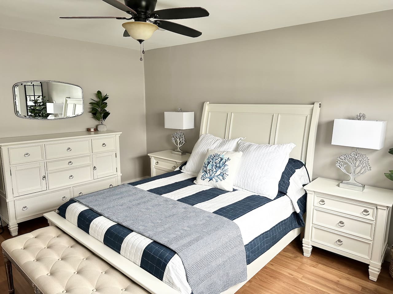Unwind in this bright, coastal bedroom featuring a comfortable bed with crisp striped linens. This well-appointed space includes a stylish tufted bench and elegant white furniture, making it easy to enjoy a restful stay before heading to the beach.