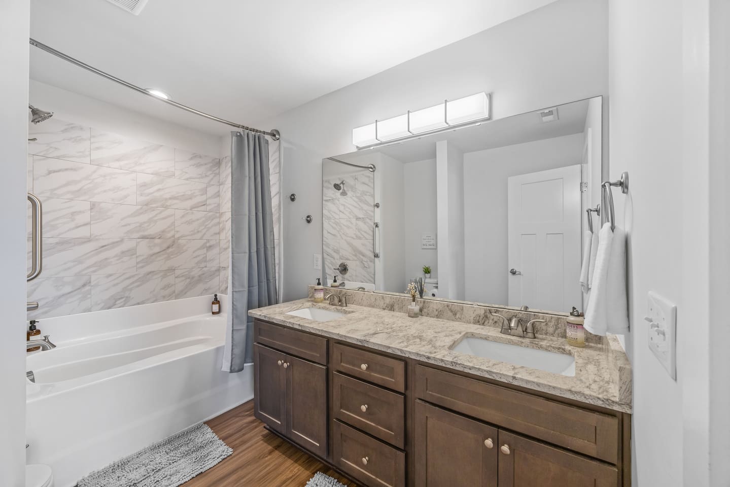 Spacious design with a double-sink vanity, granite countertops, and modern lighting.