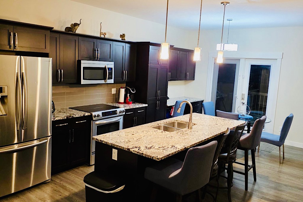 Modern kitchen w/ granite island, stainless appliances, dining nook.