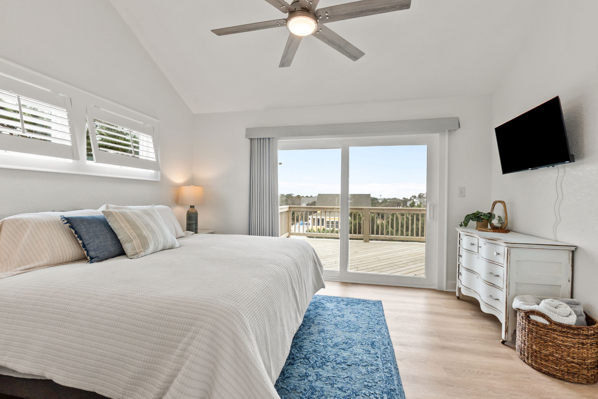 King bedroom with a TV, dresser, and sliding doors leading out to the deck.