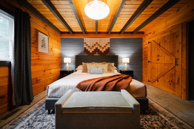 Spacious primary bedroom blending rustic cabin character with warm, modern design