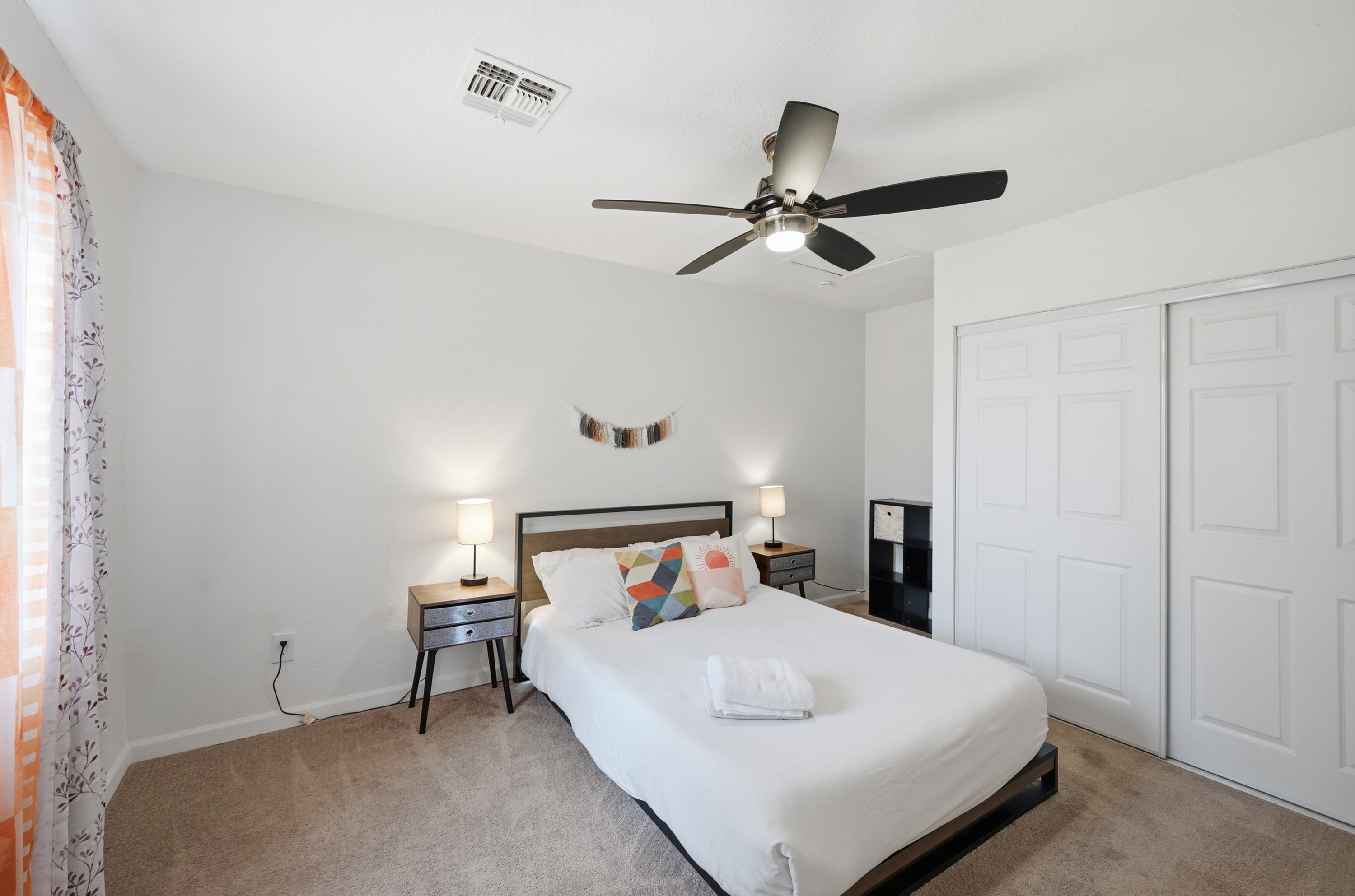 This stylish bedroom blends modern decor with warm, earthy tones, offering a restful space complete with cozy textures and thoughtful touches.
