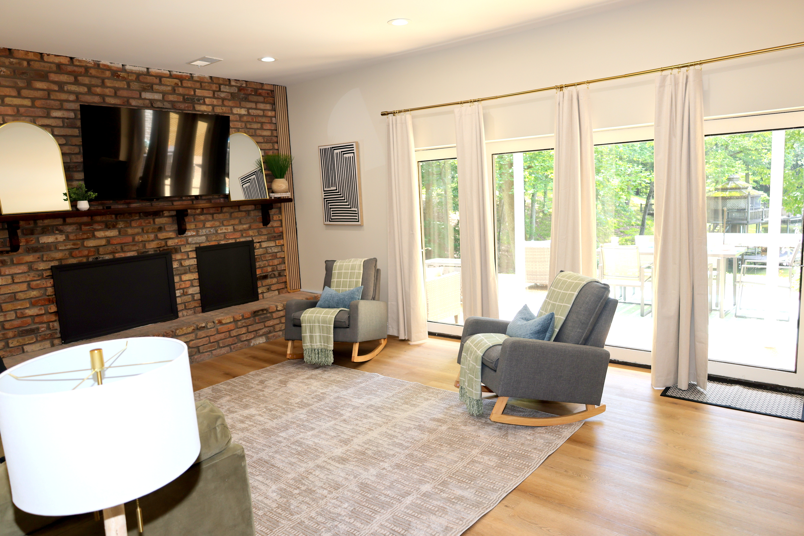 Relaxing living room with brick fireplace feature, large TV, lake views, and patio access