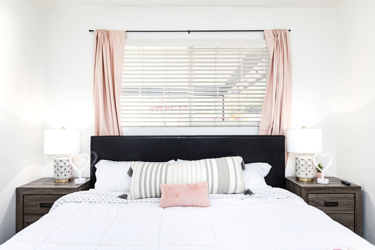 Enjoy restful nights on a plush bed with coordinated linens, pink curtains, and matching bedside lamps.

