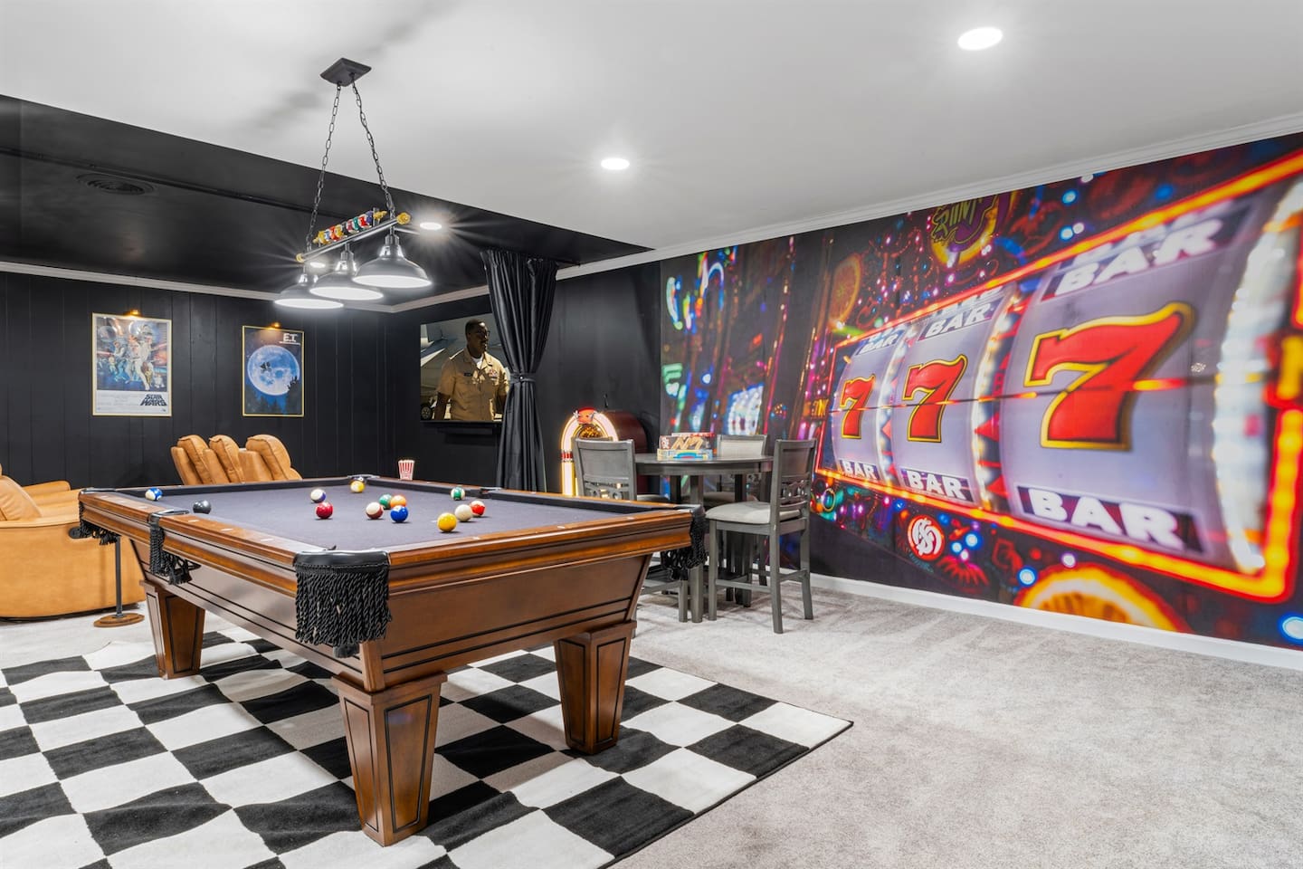 Vibrant game room with a full-size pool table, arcade games, casino-style mural, board game area, seating for plenty, and bar setup with ice maker, microwave, minifridge and TV — the ultimate entertainment space