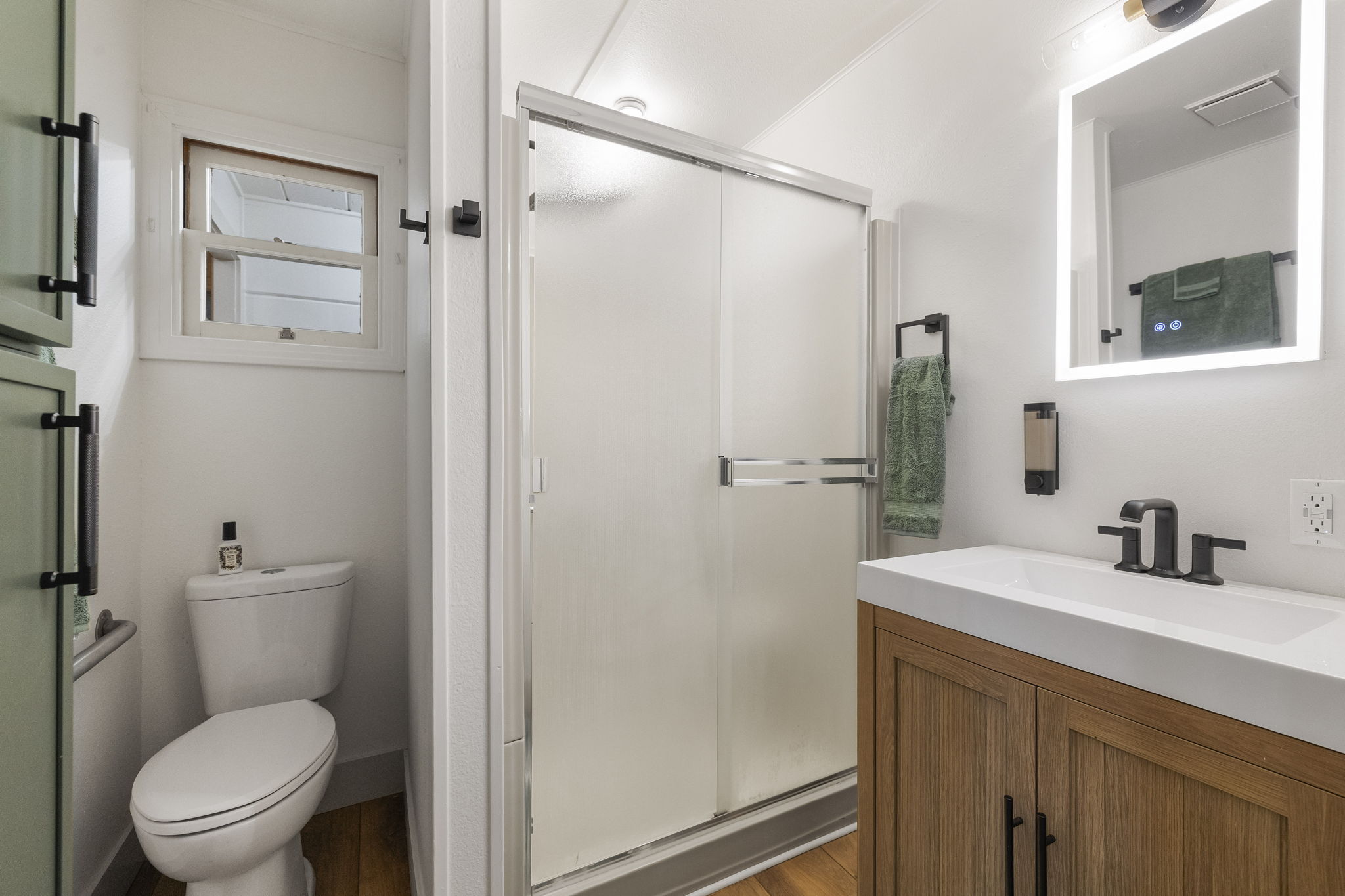 Updated master bathroom with storage for towels, shower with rainhead shower head, led mirror and bathroom supplies.