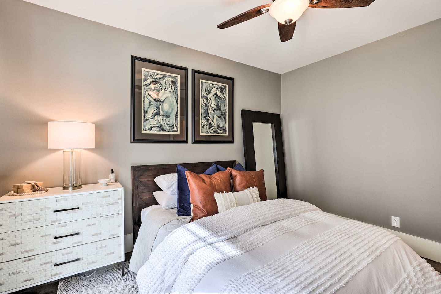 Curl up under layered linens with framed art and a full-length mirror adding the finishing touches to this restful escape.