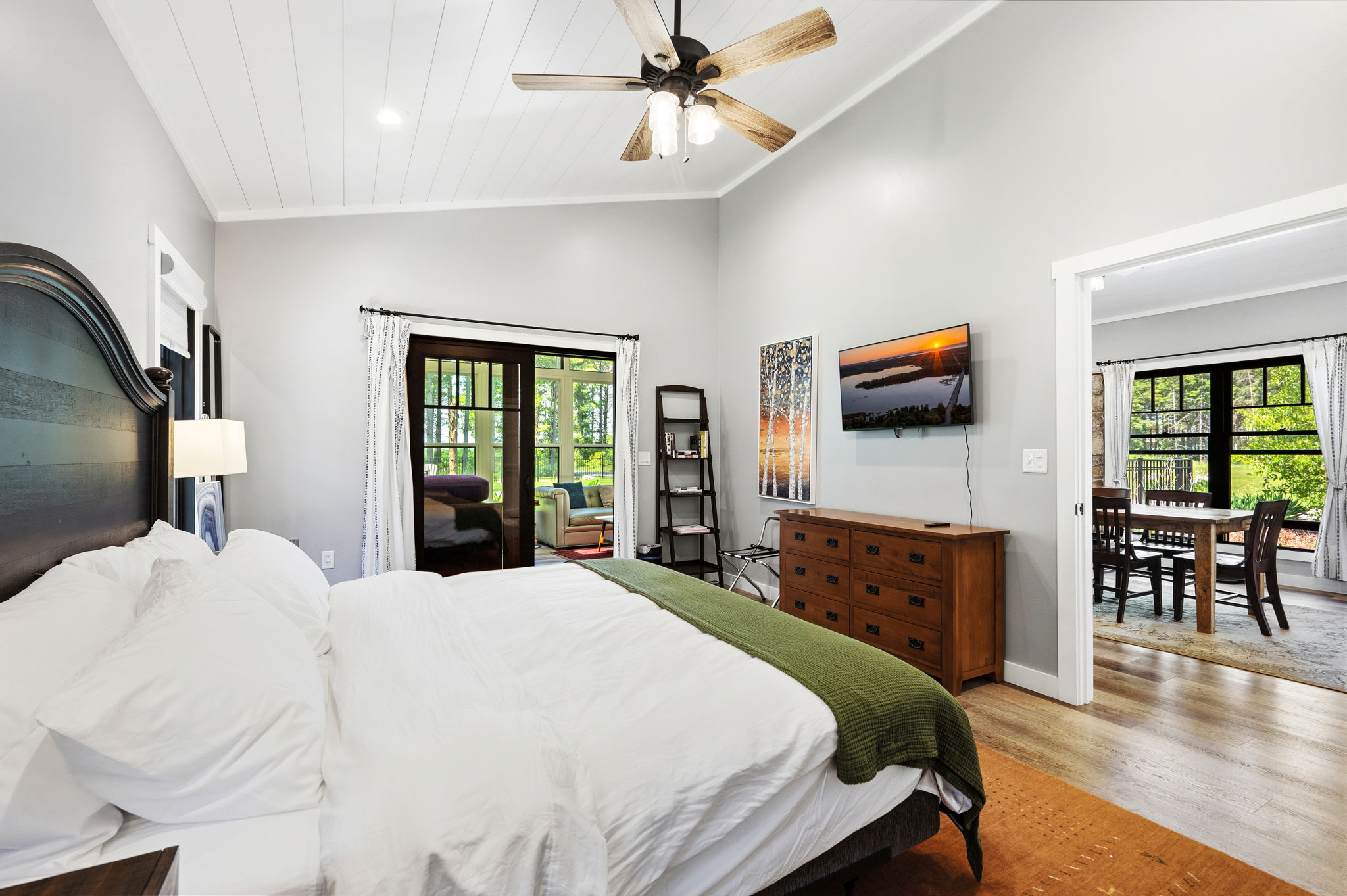 The inviting king bedroom offers crisp bedding, a mounted smart-TV, and an open flow to the dining area for effortless everyday comfort.