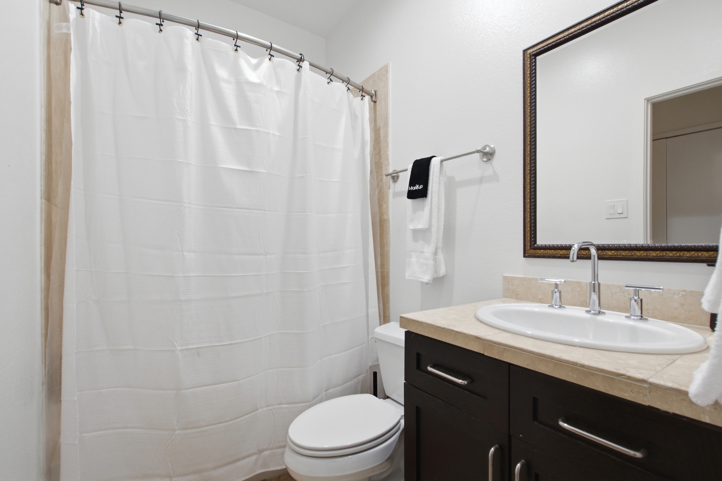 Full bathroom with walk-in shower, dark wood vanity, and classic fixtures. Stocked with Ginger Lily Farms bath essentials. Clean, functional, and ready for your arrival.