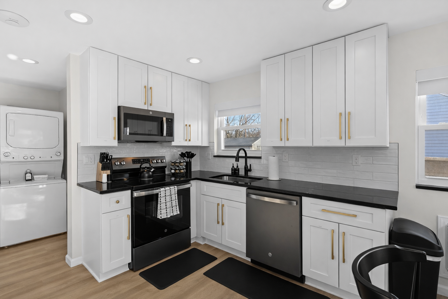 Bright, modern kitchen with crisp white cabinetry, sleek appliances, and in-unit laundry—designed for effortless cooking, convenience, and comfort.