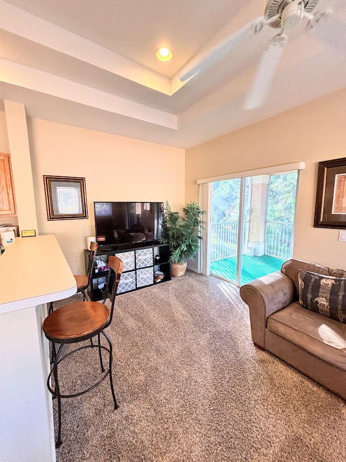 Cozy living area with breakfast bar seating, large TV, comfortable sofa, and sliding glass doors leading out to the private balcony.