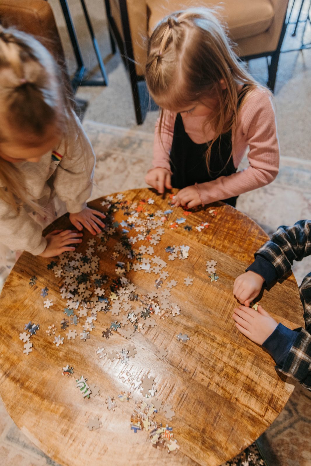 Kids working on a jigsaw puzzle on a round wood table in a Brix condo