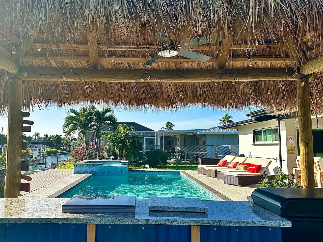 Outdoor kitchen under a large tiki hut by the pool