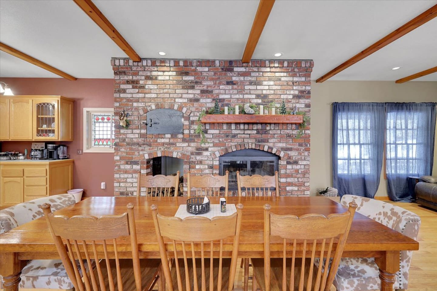 Dining area with a large table, brick fireplace, and easy access to the living room.
