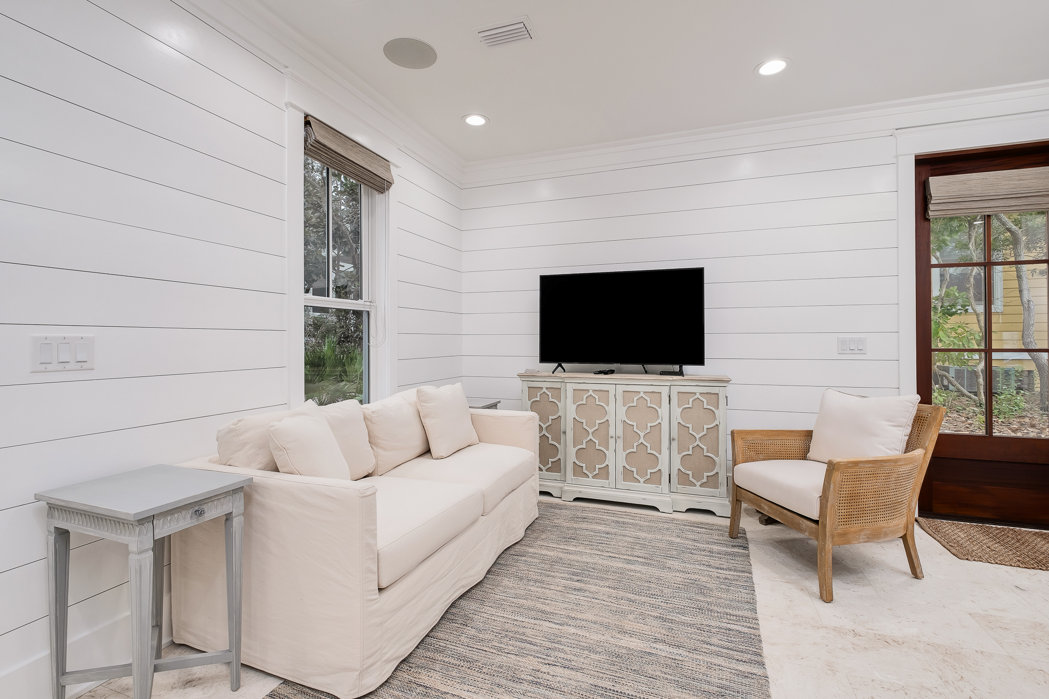 Living room has a deep sofa and arm chair, smart TV, and surround sound.
