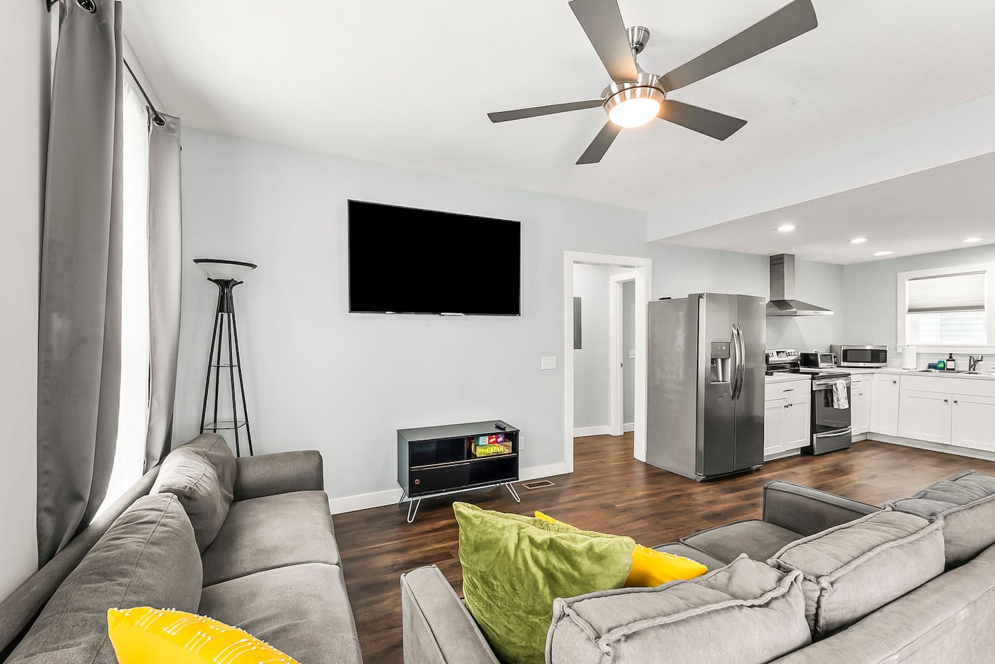 Comfort meets convenience in this inviting living room with a large TV, board games, and easy access to the kitchen and dining area.