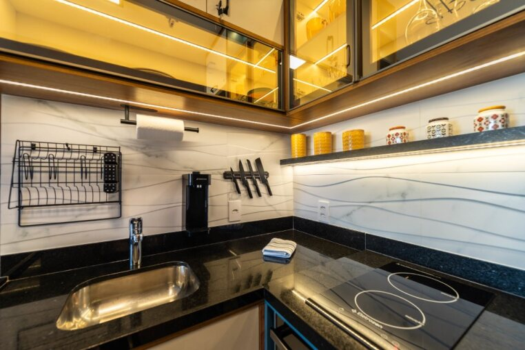 Cozinha funcional com cooktop, cuba inox, porta-facas magnético e iluminação embutida — praticidade para o dia a dia ou estadias prolongadas.