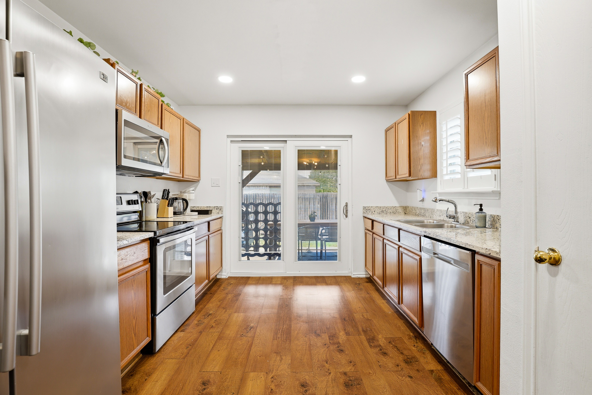 Stainless kitchen with electric stove, full-size refrigerator, microwave, and granite countertops — open to the dining and living area for easy entertaining. Fully stocked with cooking basics and utensils.