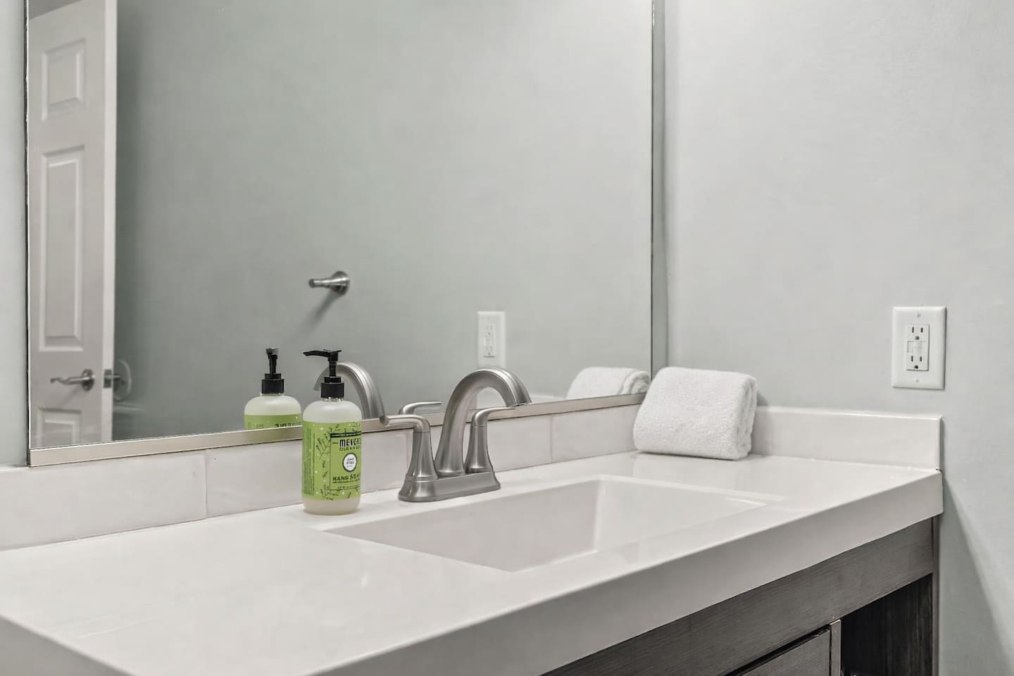 Close-up of the sink and vanity featuring a modern faucet, clean countertop, and provided hand soap.