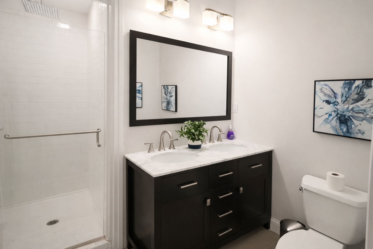Refresh in the spacious main bathroom, featuring a double vanity with marble tops and a large glass-enclosed walk-in shower.