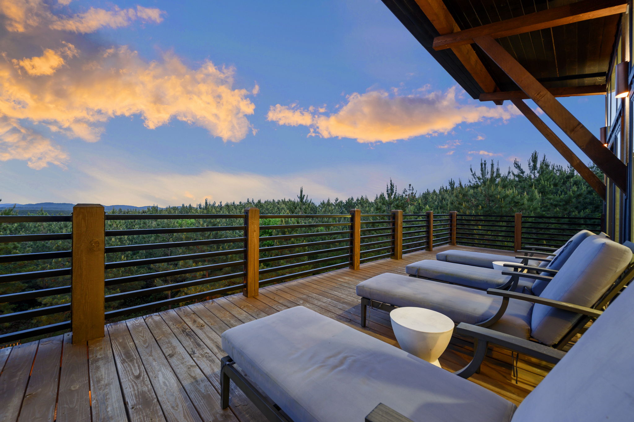 Modern Broken Bow cabin with expansive second-story deck, outdoor lounge seating, and breathtaking sunset views.
