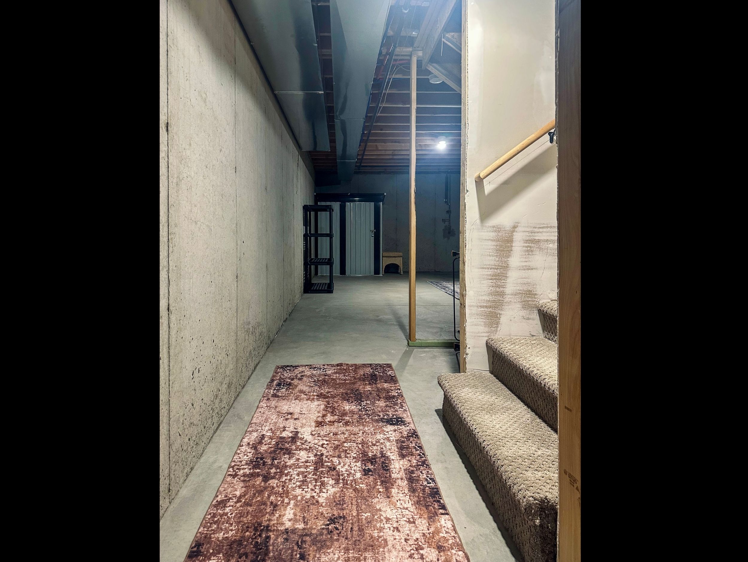 Spacious basement landing leading toward the west storage area, providing practical overflow space that keeps main living areas uncluttered.