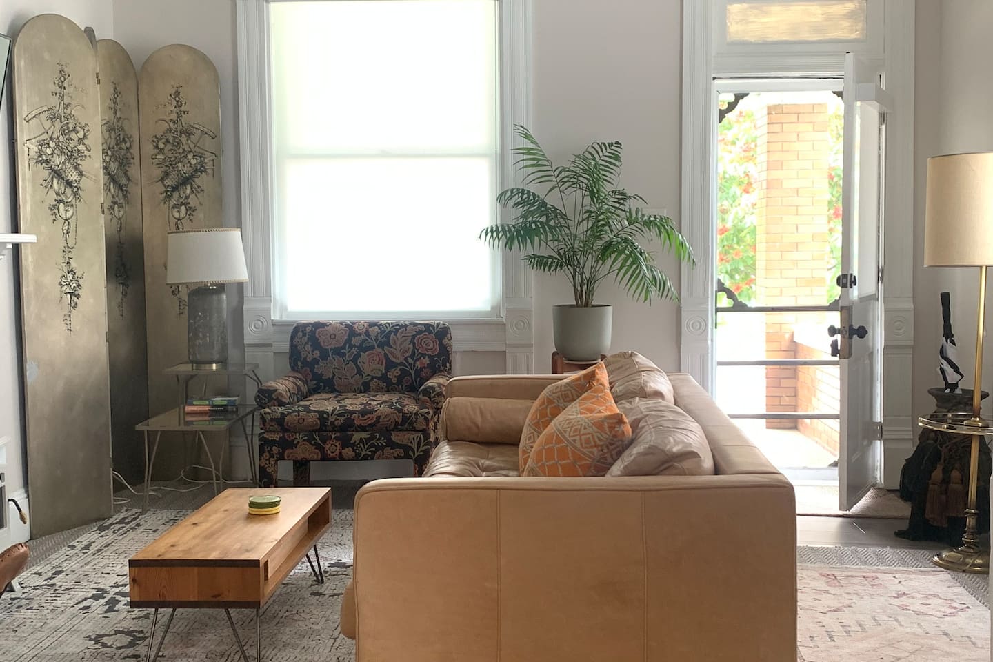 Front door entry fills this living area with natural light - bright, inviting and curated with comfortable seating and vintage charm. 