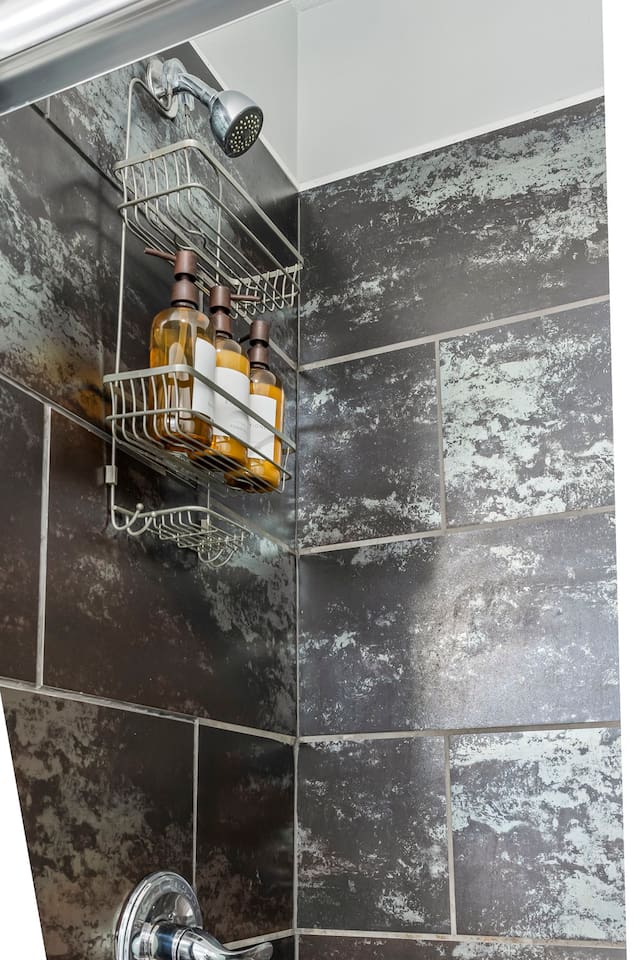 Close-up of the shower area featuring built-in storage rack and provided bath essentials.