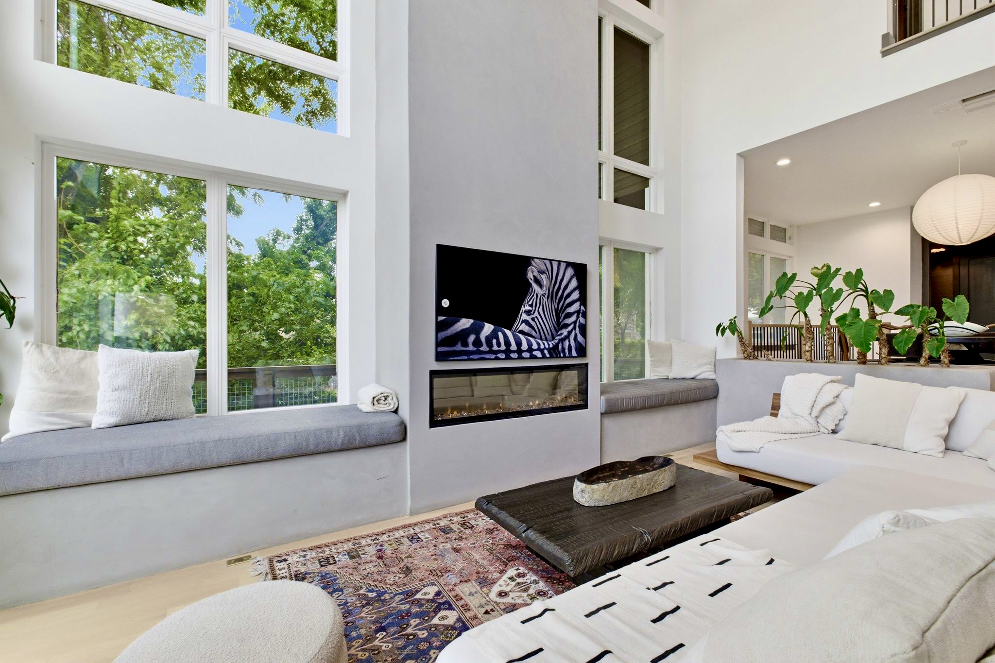Bright living space w/ a fireplace, plush sofa & warm layered textures for effortless unwinding.
