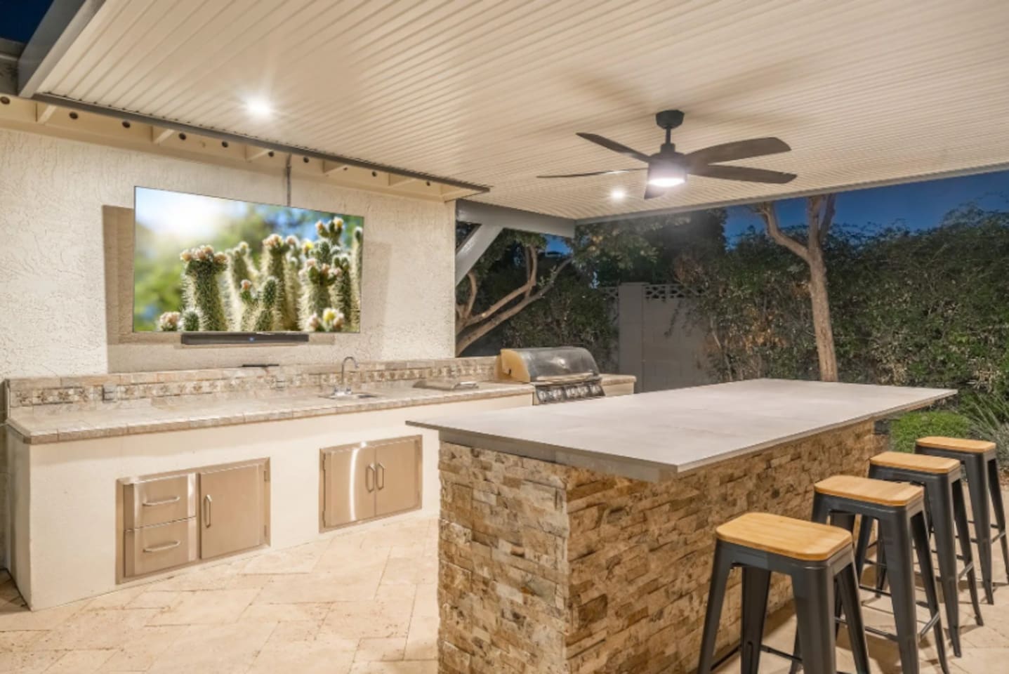 Stainless steel grill, stone counters, and a mounted TV — everything you need to cook, entertain, and never miss the game.