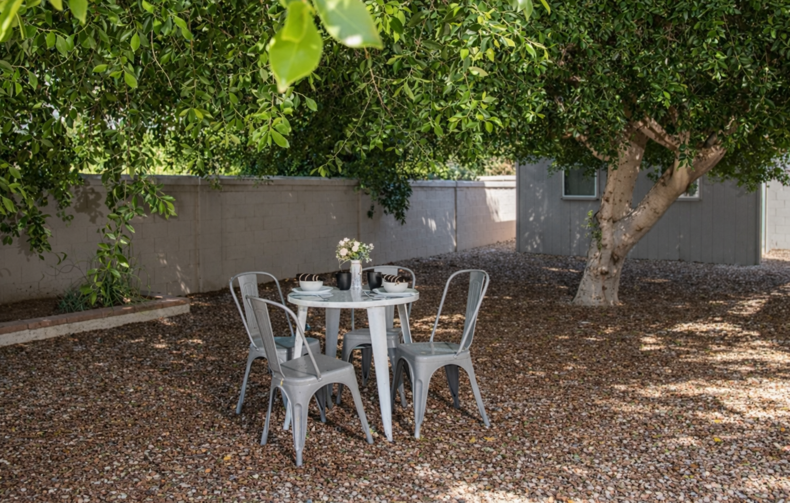 Enjoy peaceful mornings or shaded lunches at this charming backyard table nestled under mature trees and desert sky.