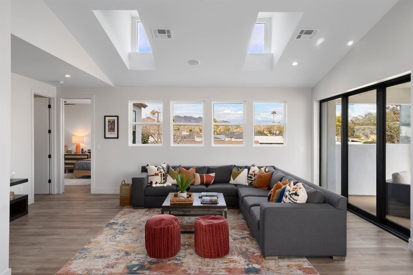 Unwind in the cozy living room featuring a long L-shaped sofa, a center table showcasing books and decor, two fabric seats, and a TV with a sound bar for your entertainment needs.
