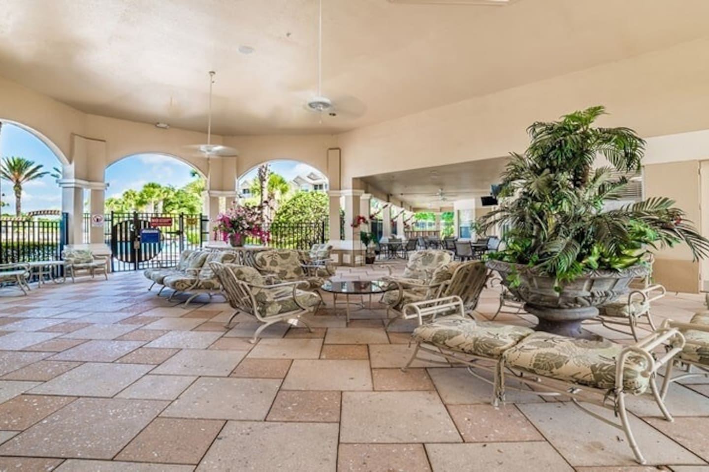 Covered patio with cushioned seating and garden views.

