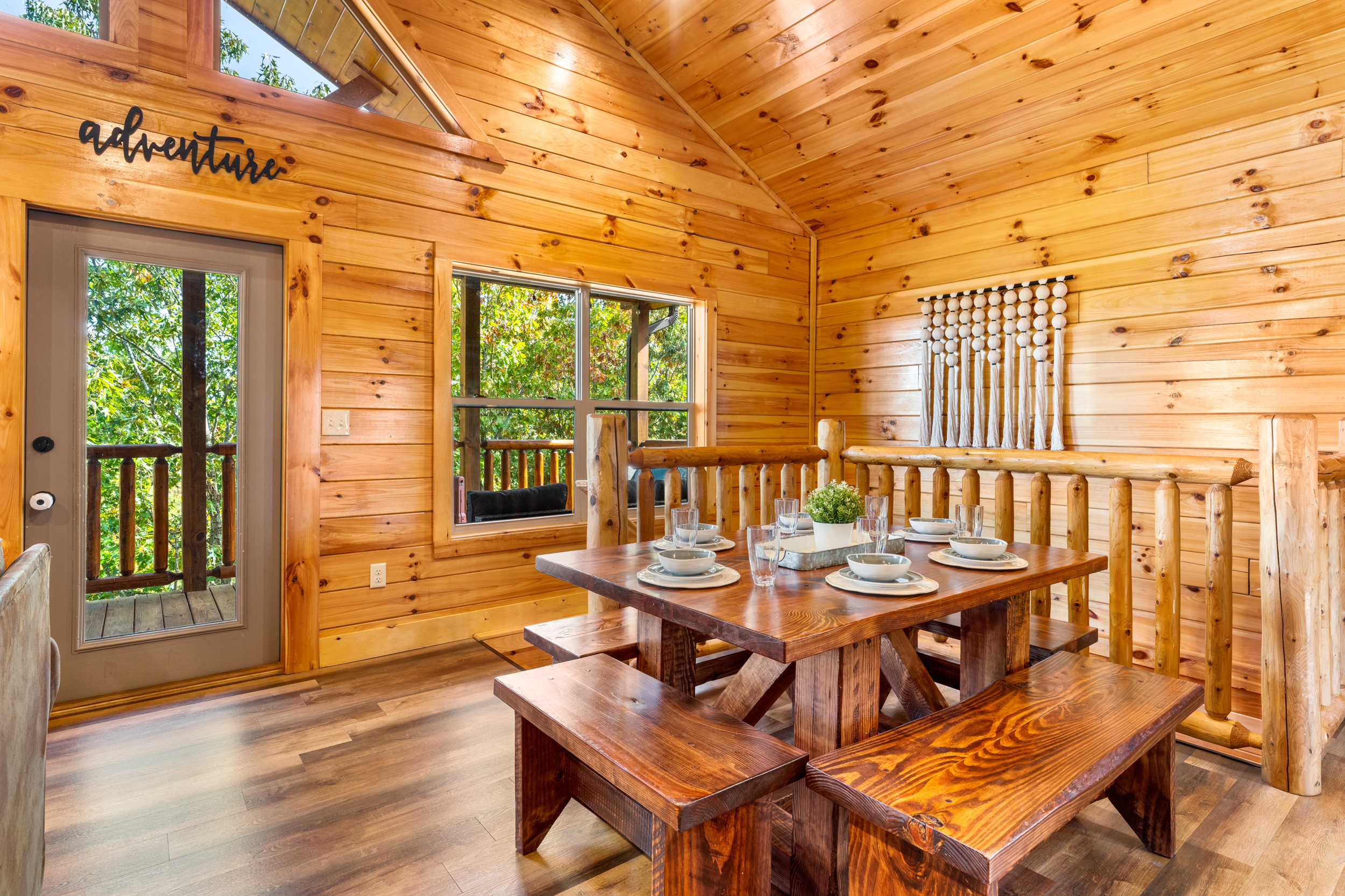 [Dining Area] Solid wooden dining table with benches and seating for 8, soft lighting, and décor that creates a warm gathering space. Just outside the door in your first-floor balcony with gas grill and picnic table.