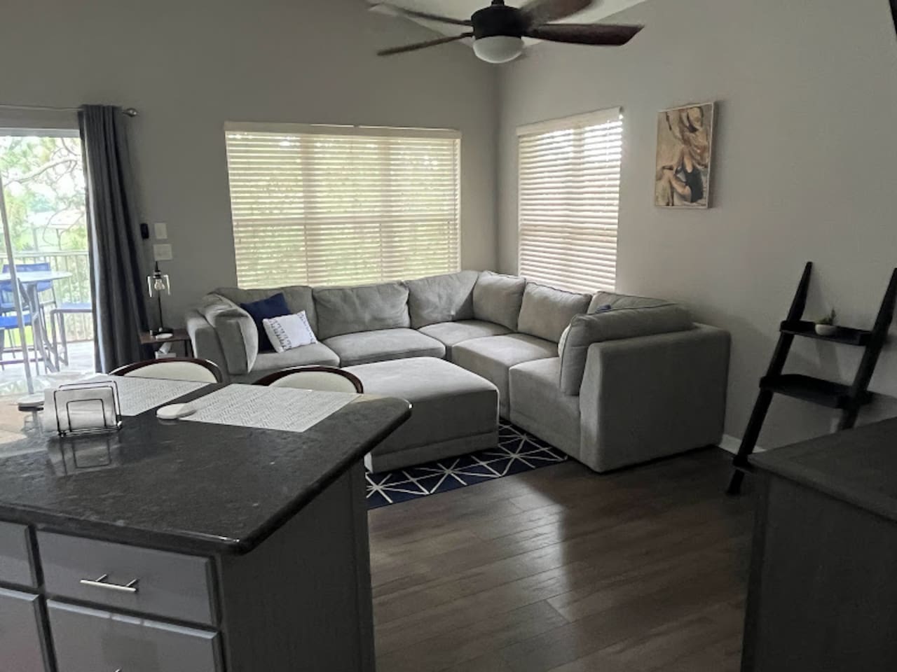 Spacious living area with comfortable sectional seating, wood-look flooring, and large windows for a bright, relaxing feel.