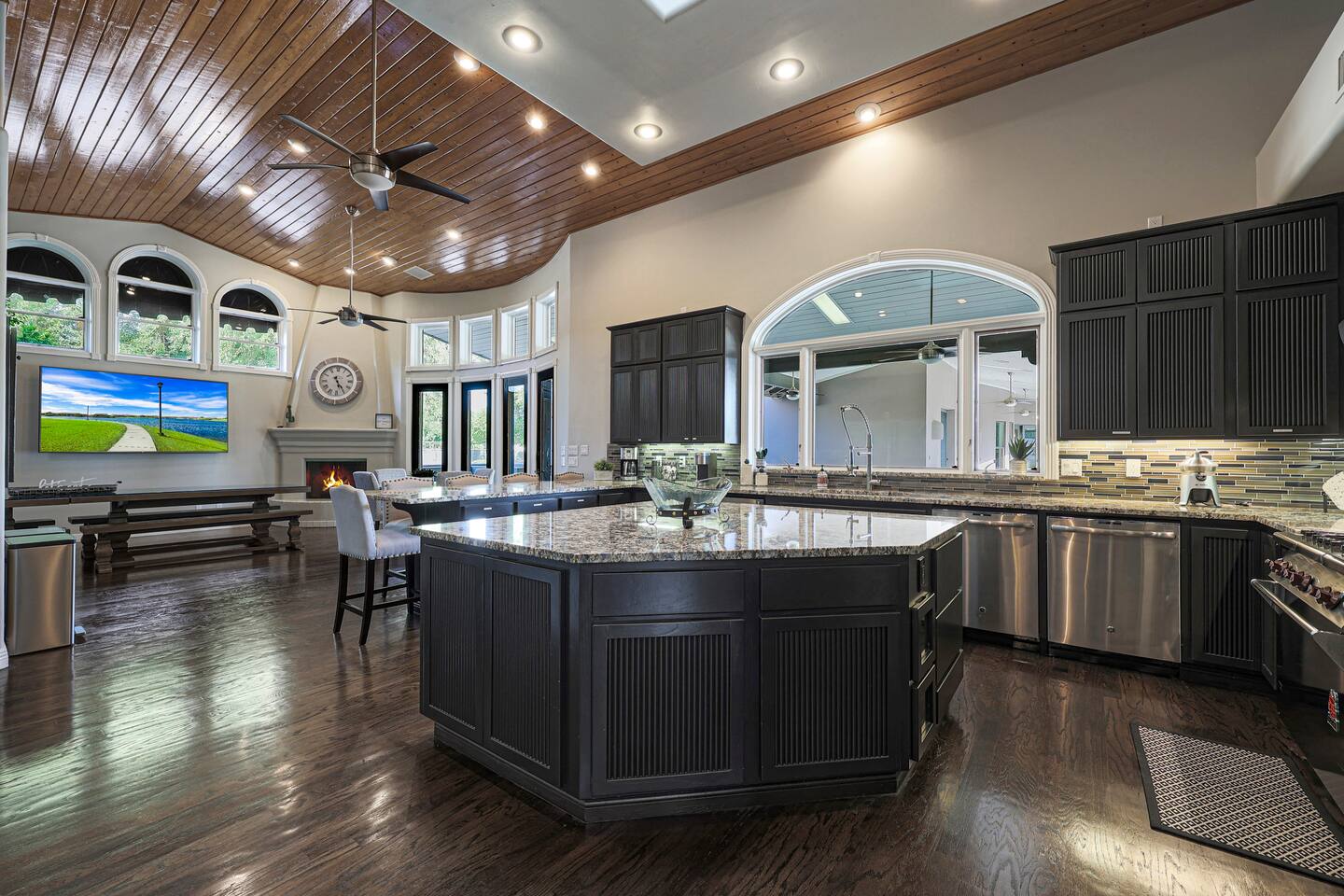 This expansive kitchen is a culinary dream—featuring a grand central island, granite countertops, and seamless views into the adjoining lounge and outdoor retreat.