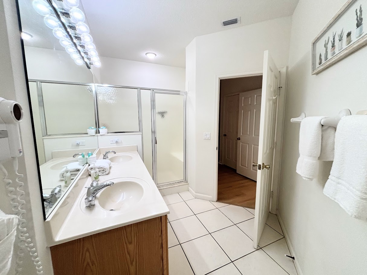 Bright bathroom featuring a large vanity, tile flooring, and a clean shower enclosure.