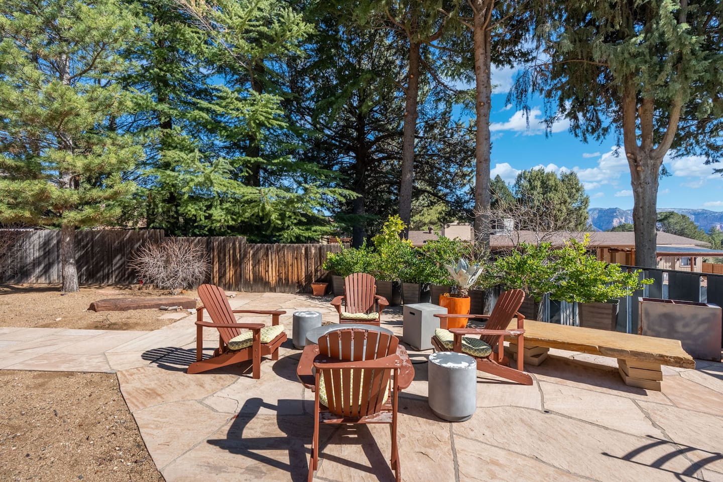 Spacious backyard patio with Adirondack seating and a central fire pit area, surrounded by mature trees and mountain views — a perfect gathering spot to relax and enjoy the fresh air.