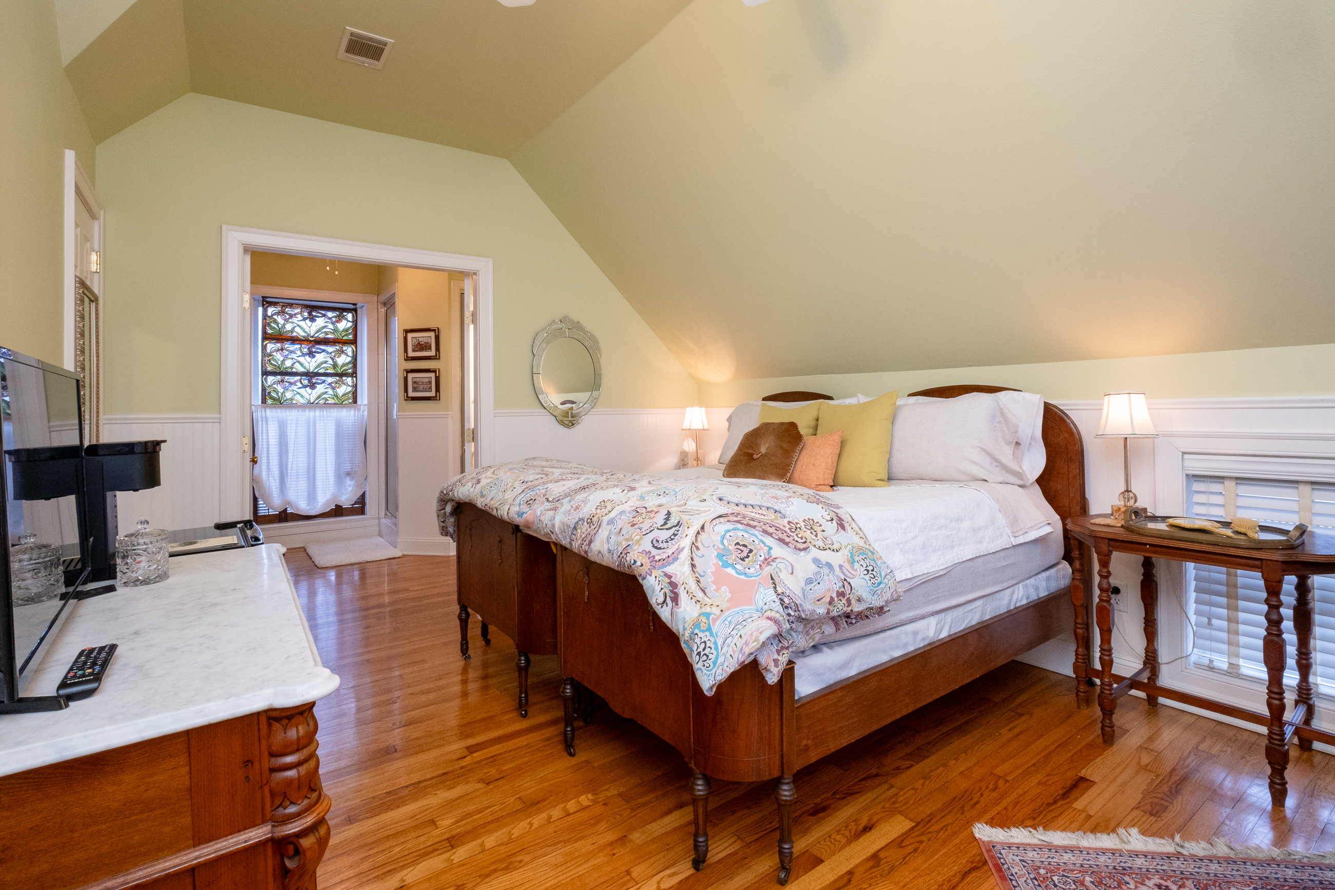 Garden Spa Suite bedroom with a king bed, sloped ceiling, and original hardwood floors.