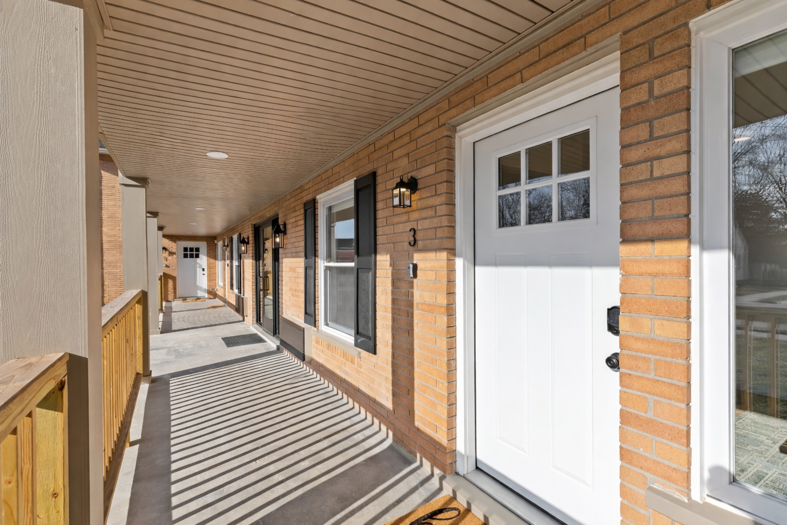Welcoming covered walkway with classic brick exterior, warm lighting, and private entry—clean, quiet, and inviting from the moment you arrive.