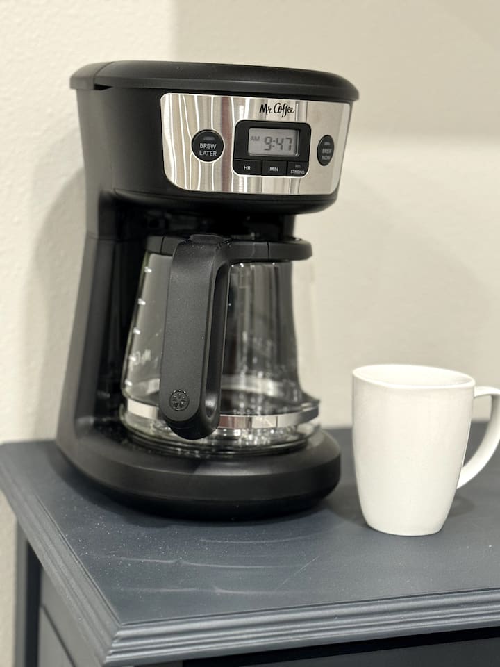 Drop coffee pot maker located on the coffee and wine bar.  Check the freezer for ground coffee.