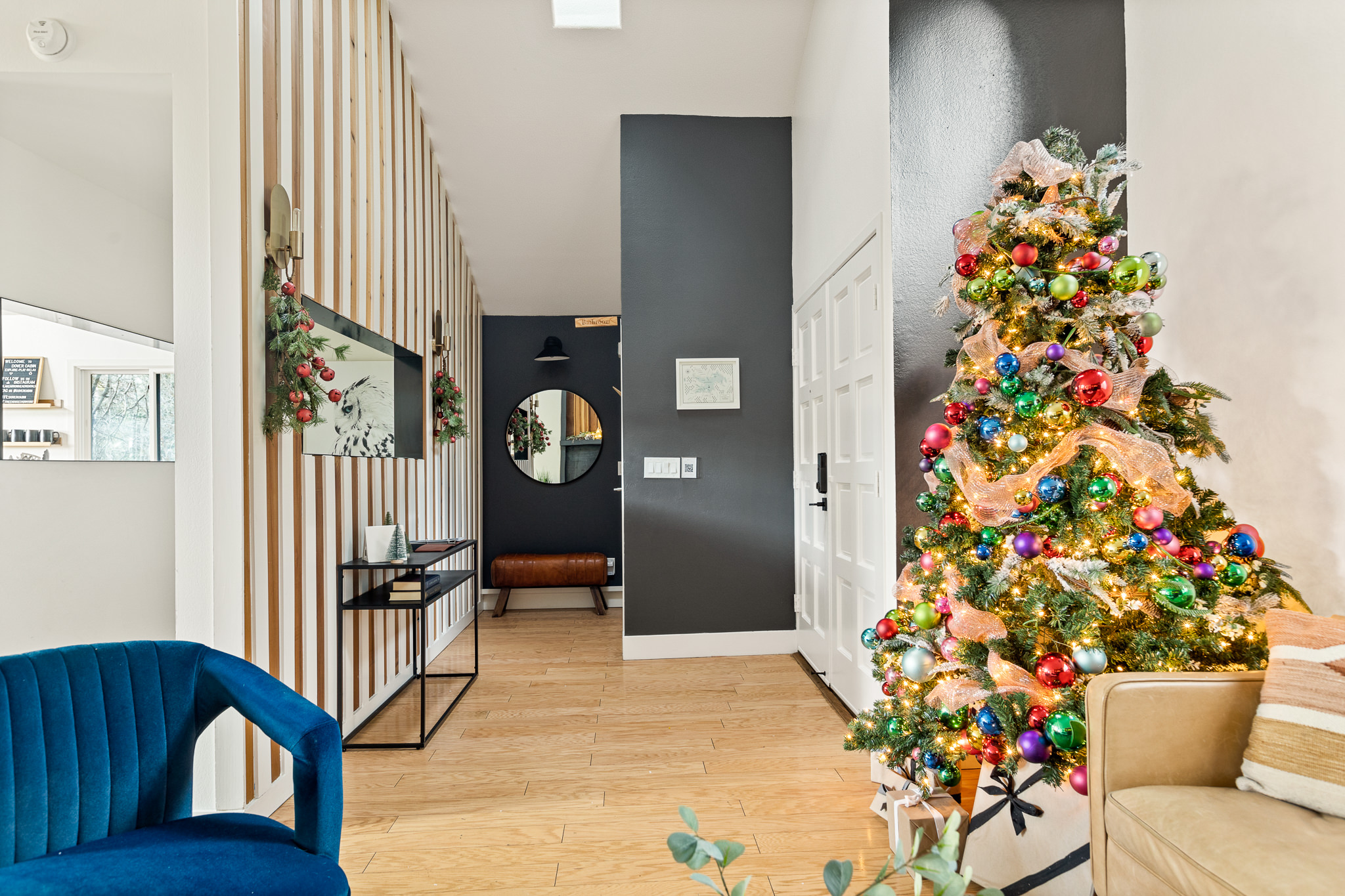 Festive mountain cabin entry with a beautifully decorated Christmas tree, warm lighting, and modern wood accents—creating a bright, welcoming space for a cozy holiday stay in Lake Arrowhead.