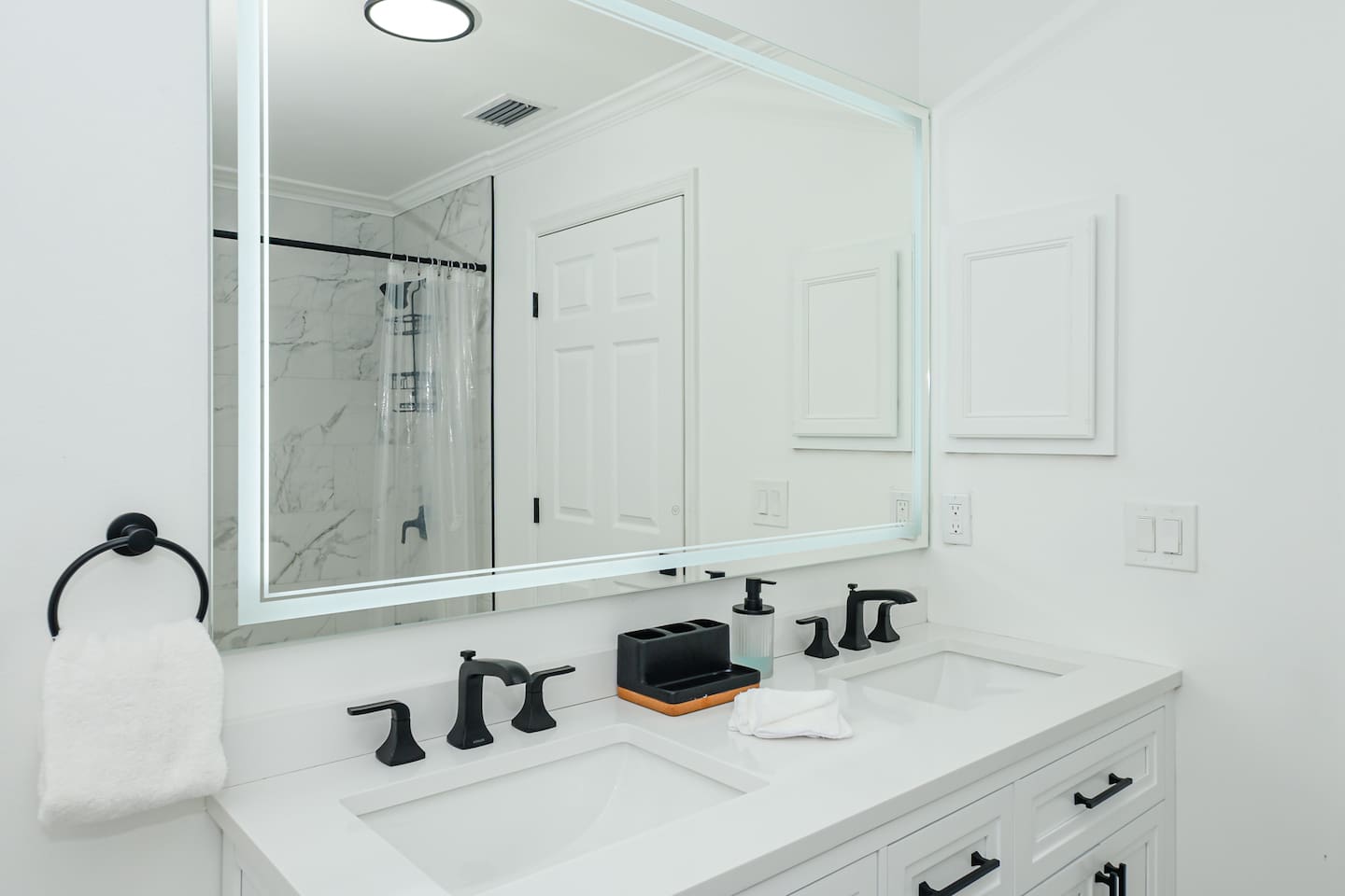 Spacious all-white and black interior bathroom with a stylish sink, combining modern elegance and functionality.