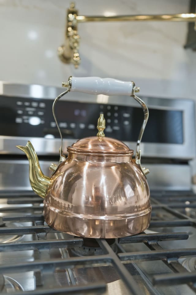 Classic copper tea kettle on the gas stove—perfect for preparing tea, coffee, or hot drinks during your stay.