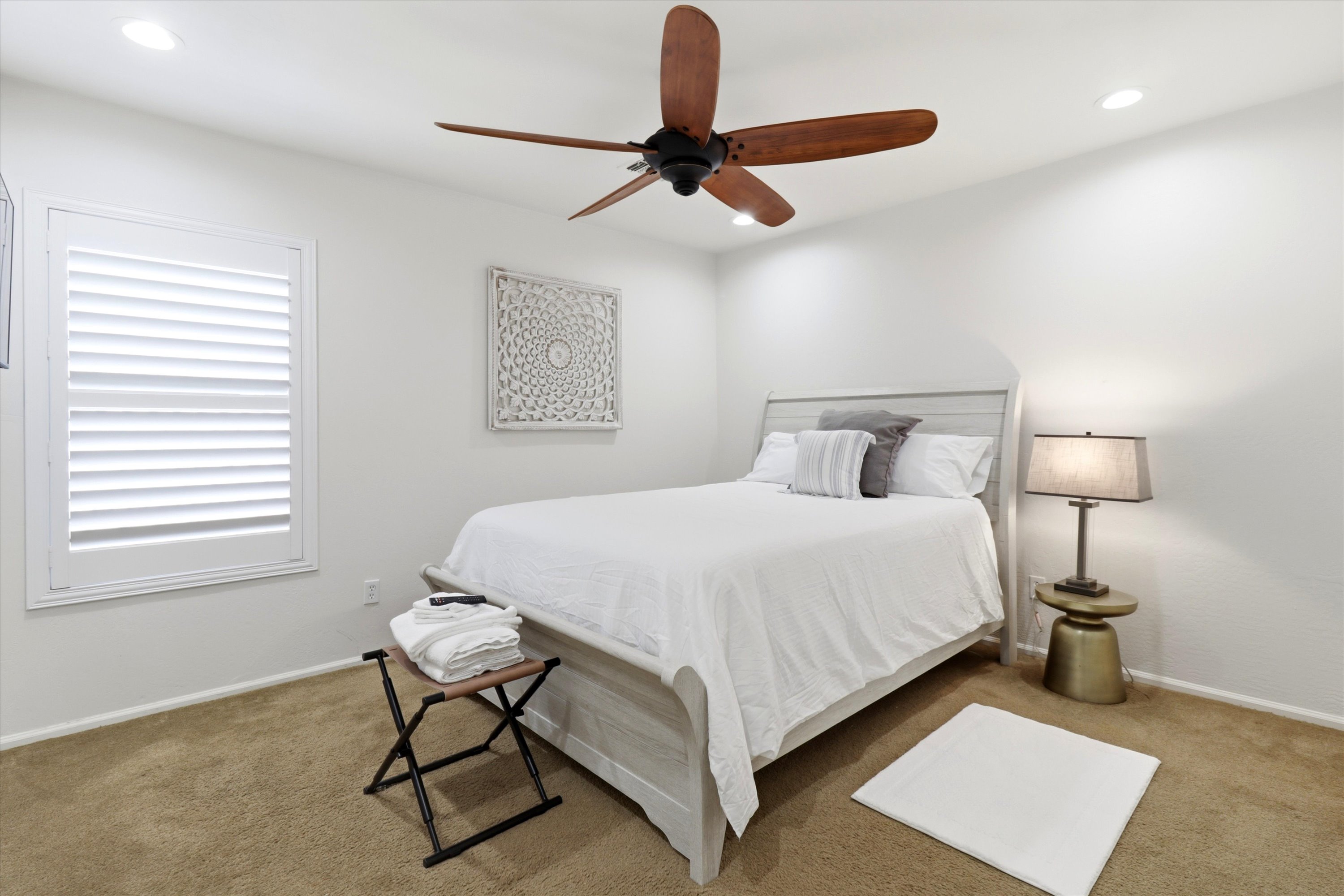Bedroom with soft bedding, ceiling fan, and a simple spot to rest and recharge.
